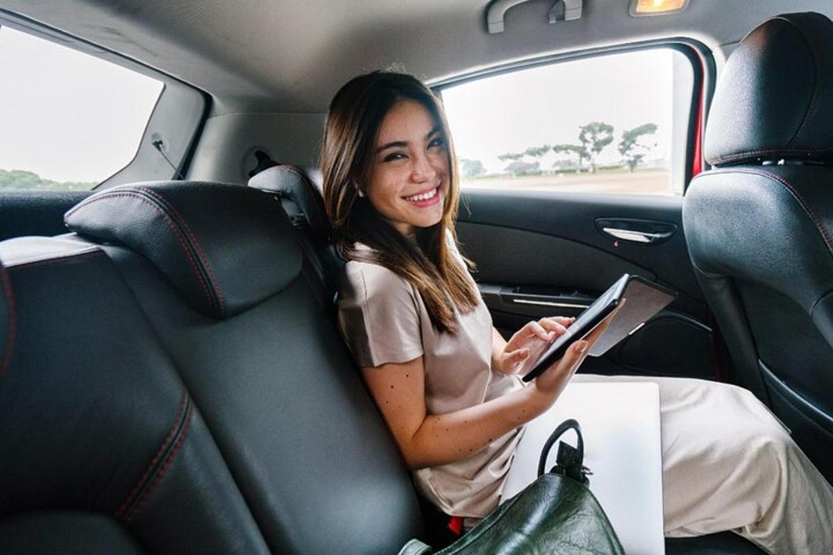 Una mujer sentada en el asiento trasero de un coche usando una tableta.