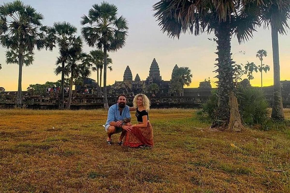 a man and woman sitting in a field with palm trees