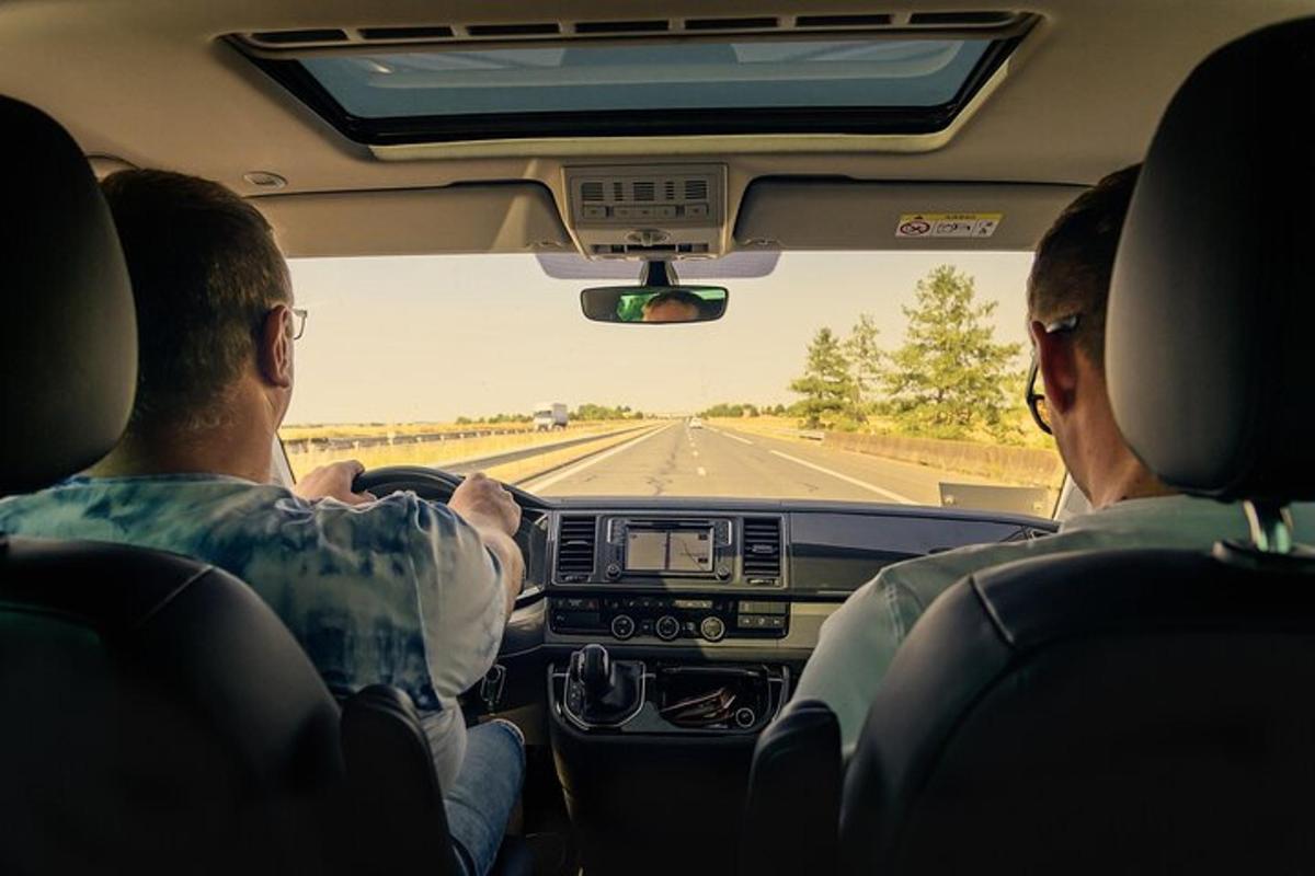Dos personas sentadas en un coche mirando por el parabrisas.