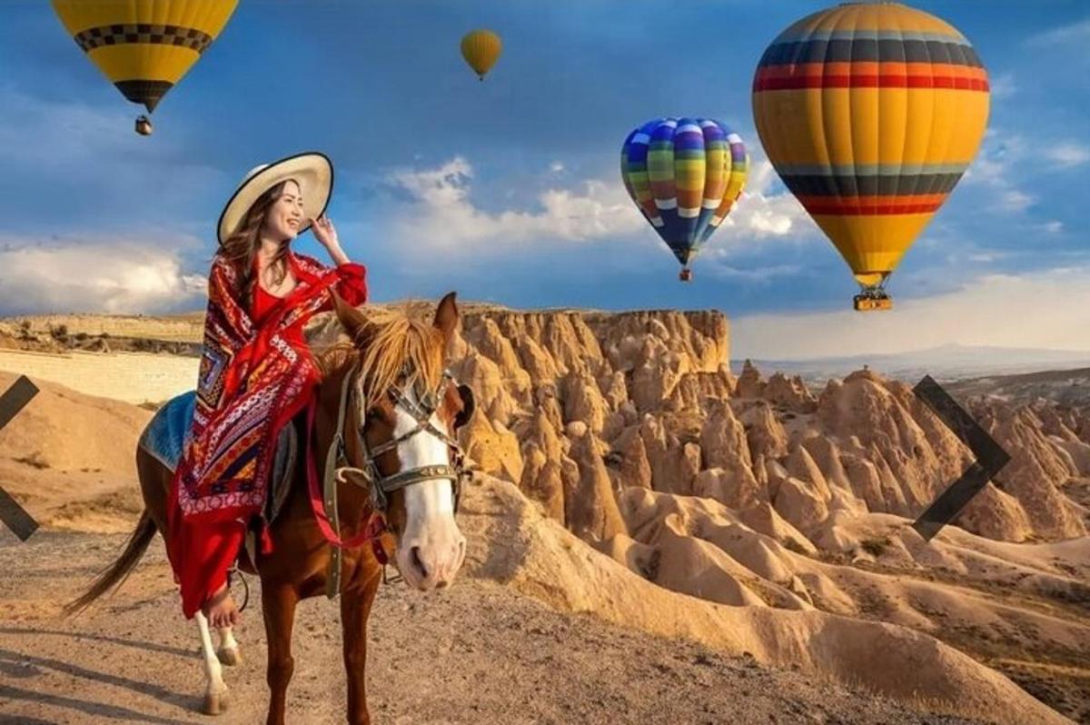 uma mulher cavalgando um cavalo no deserto com balões de ar quente