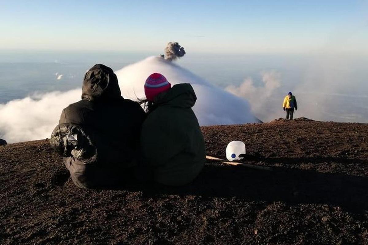 两个人坐在山上看着火山