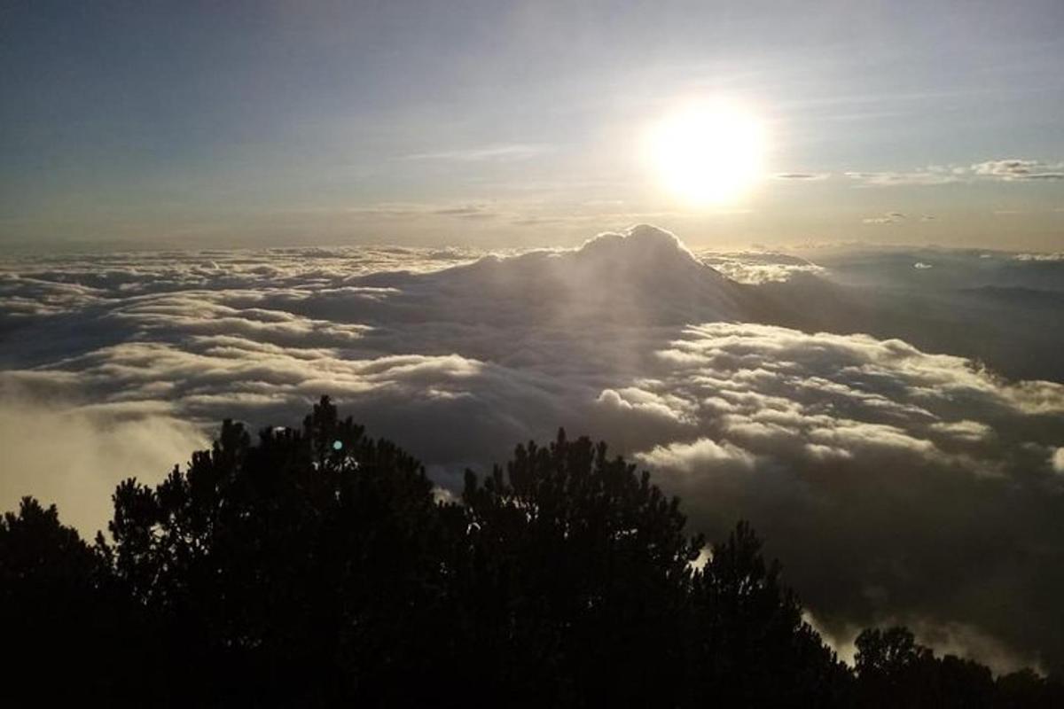 a view of a mountain with the sun above the clouds