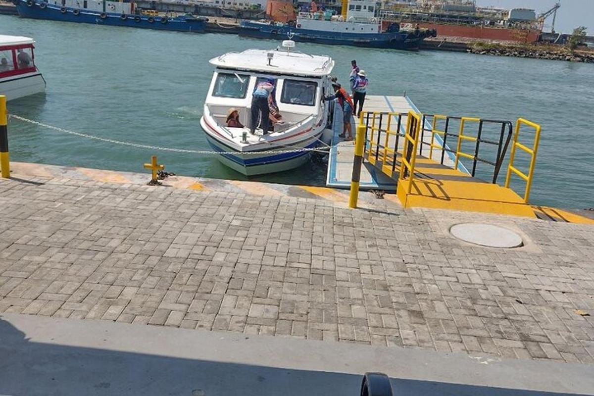 sebuah perahu berlabuh di dermaga dengan orang-orang dan seekor anjing di atasnya