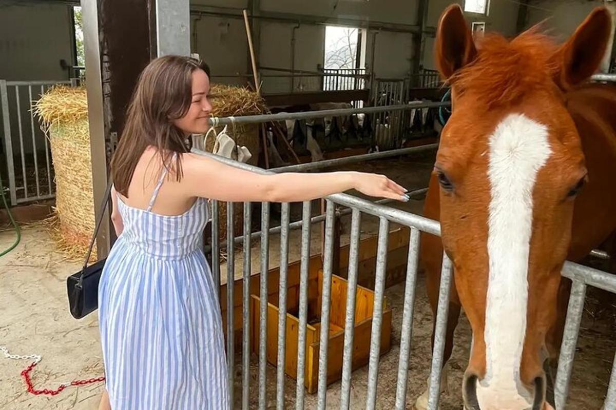 uma mulher de vestido listrado acariciando um cavalo