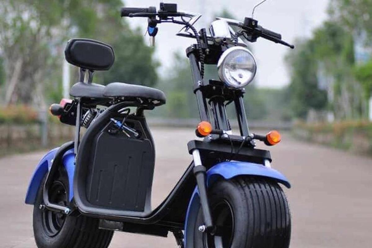 một chiếc xe tay ga nhỏ màu xanh đỗ trên phố