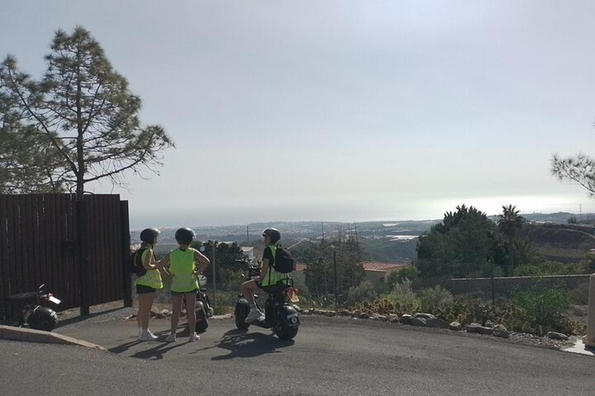un grup de oameni care stau lângă o motocicletă pe un drum