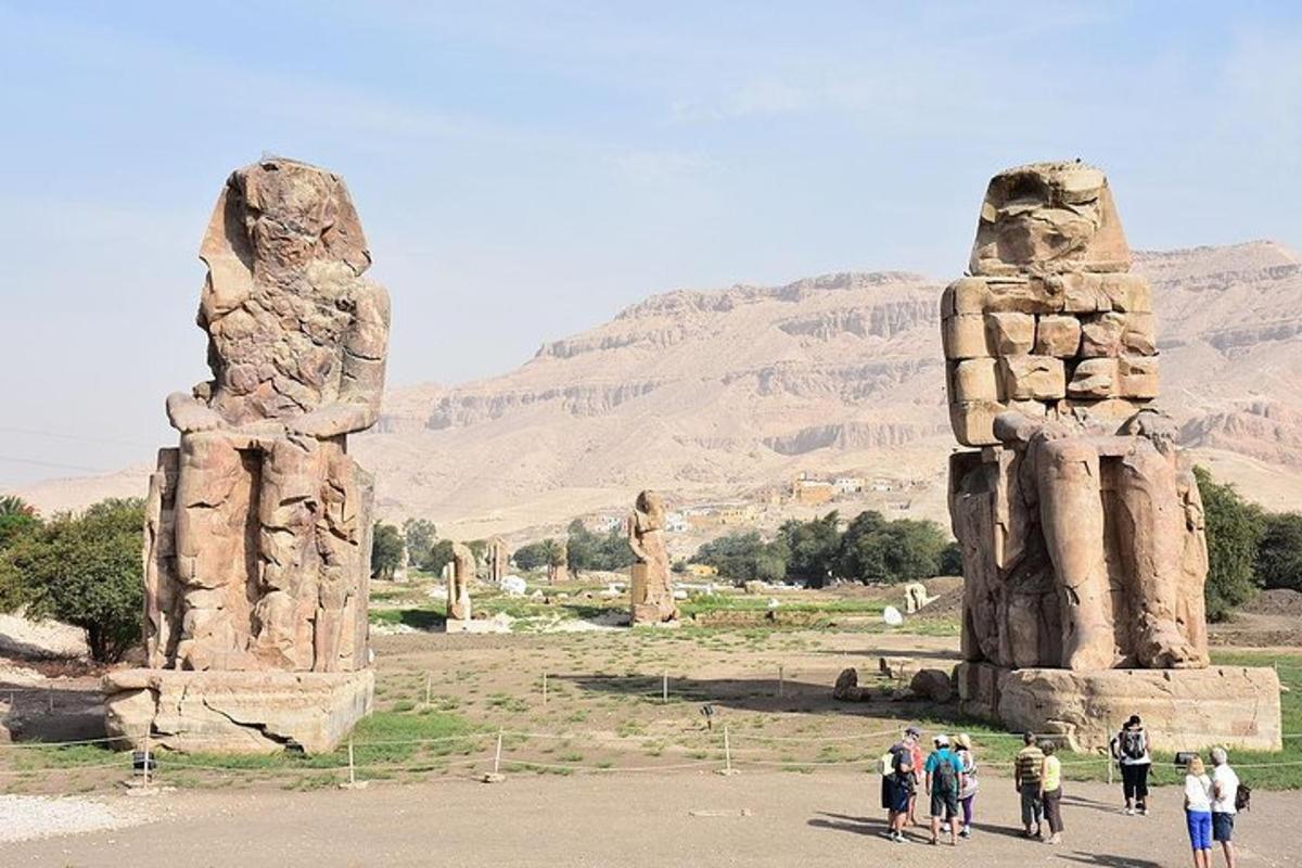 un gruppo di persone che camminano vicino a due grandi statue di pietra