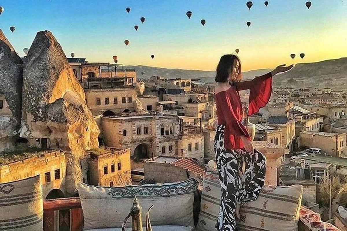 Μια γυναίκα που στέκεται πάνω από μια πόλη με μπαλόνια θερμού αέρα