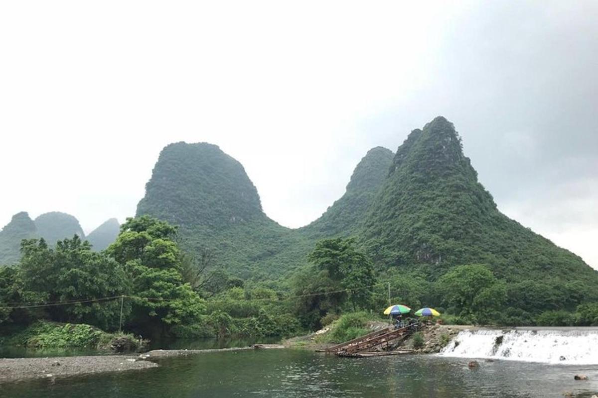sekumpulan manusia dengan payung di sungai dengan gunung