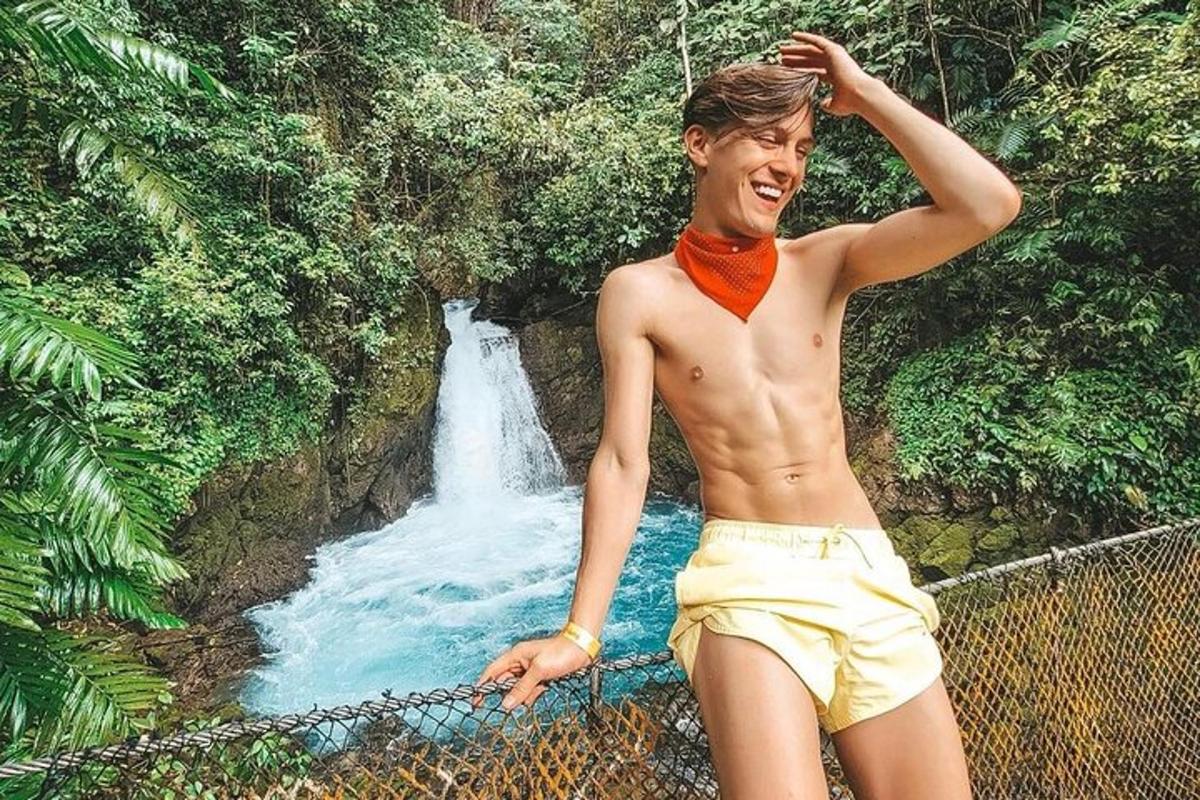 a young man standing in front of a waterfall
