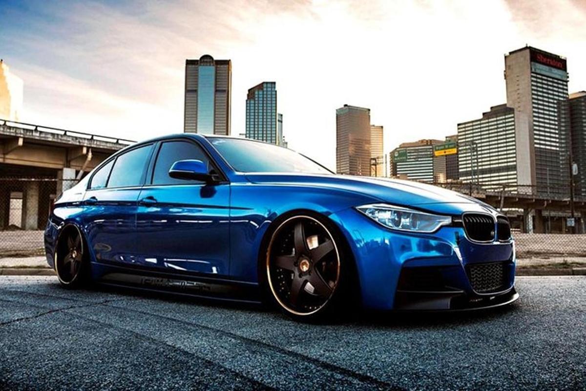 un cotxe BMW blau aparcat davant d'una ciutat