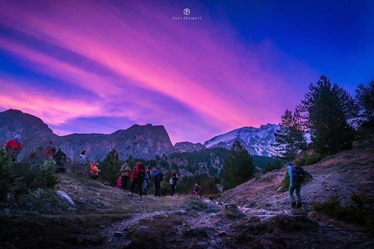 sekelompok orang berjalan mendaki gunung saat matahari terbenam
