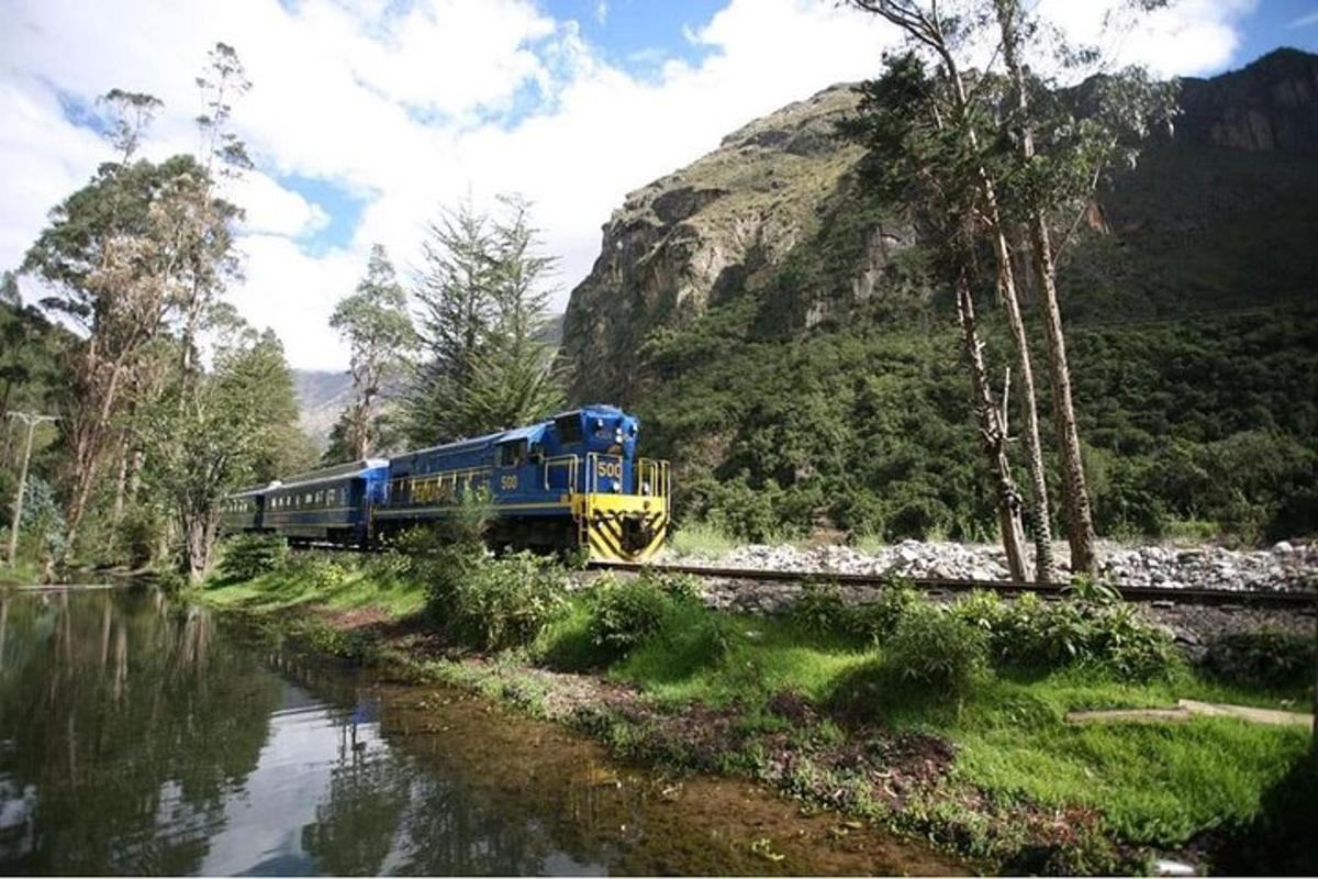 un tren blau i groc que viatja per vies al costat d'un riu