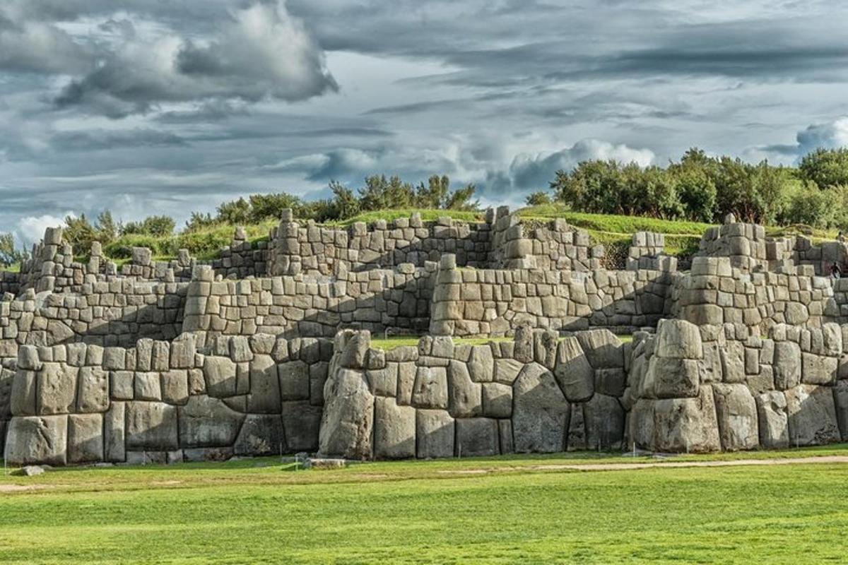 a large stone wall in a field with grass