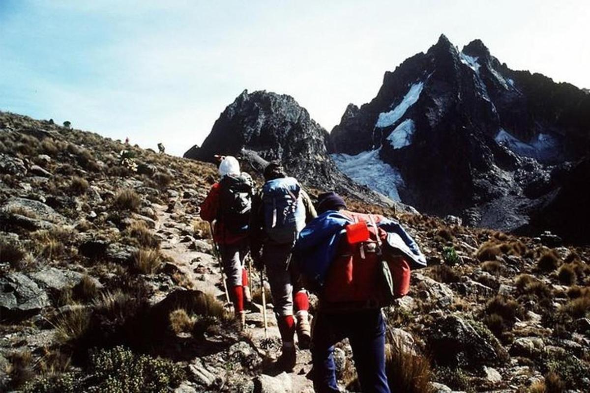 en gruppe på tre personer som går opp et fjell