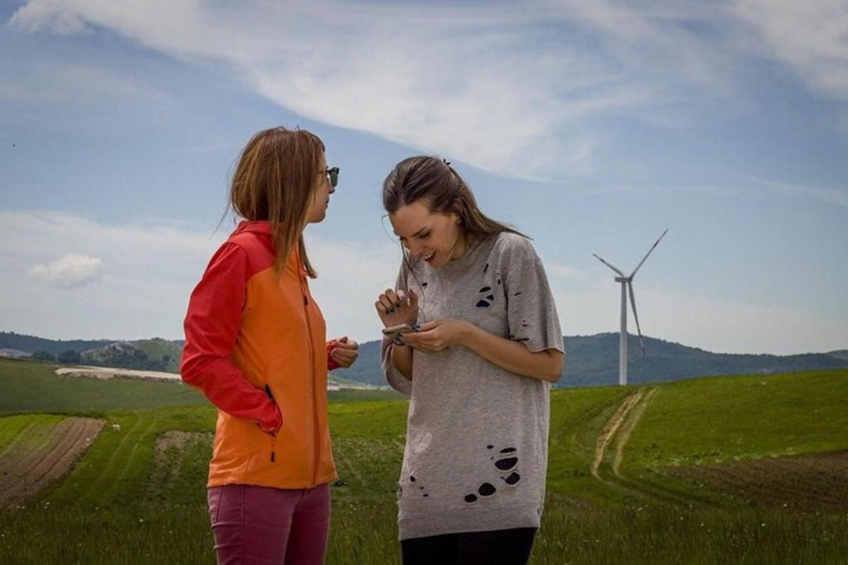 dvě ženy stojící na poli a dívající se do mobilního telefonu