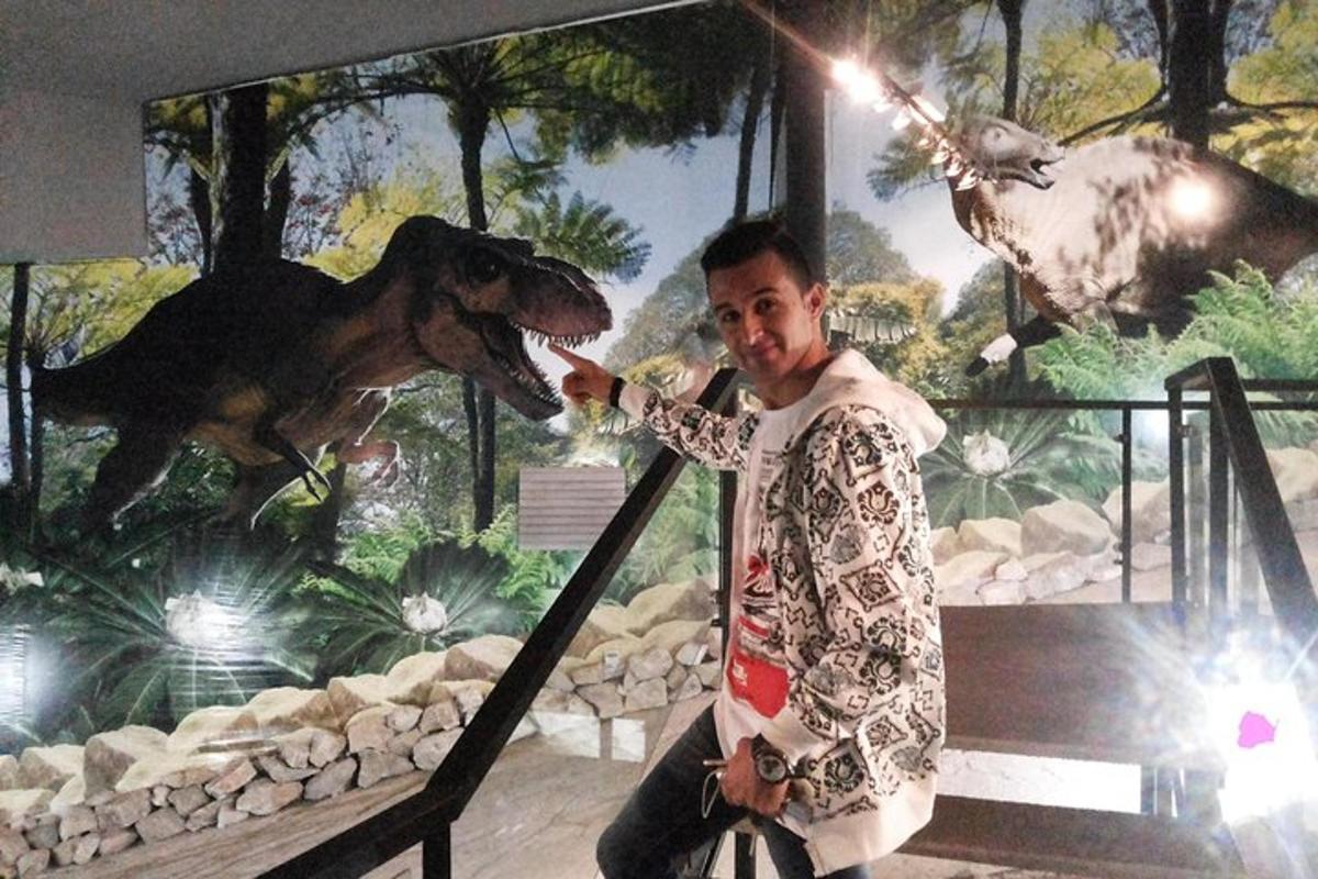 seorang pria berdiri di depan mural dinosaurus