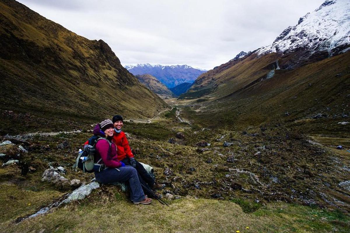dos personas sentadas en una roca en una montaña