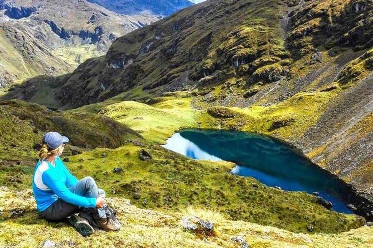 žena sedící na úbočí hory s výhledem na jezero