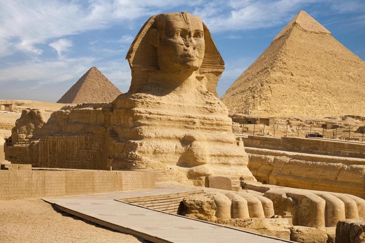 en statue av sfinksen foran pyramidene