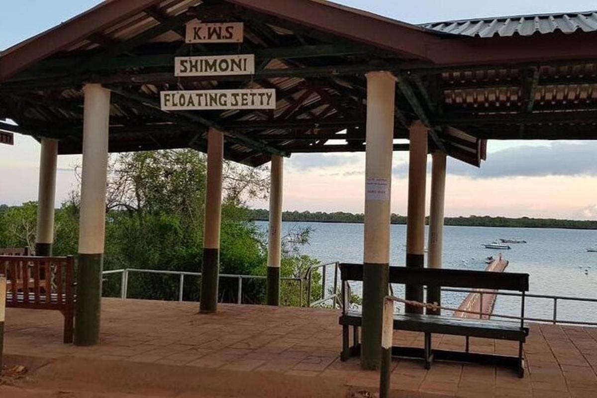 Un banco debajo de un cenador junto al agua.