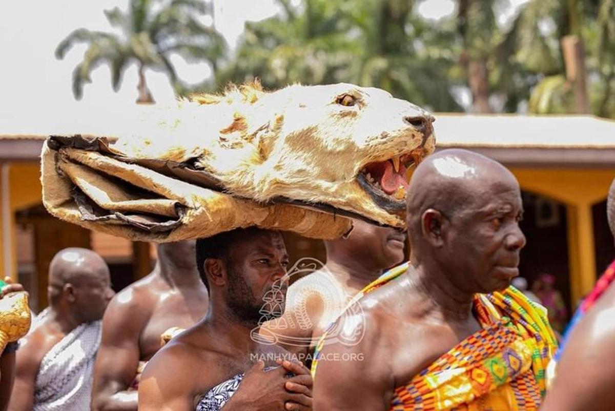 un gruppo di uomini che trasportano un animale decapitato sulla testa