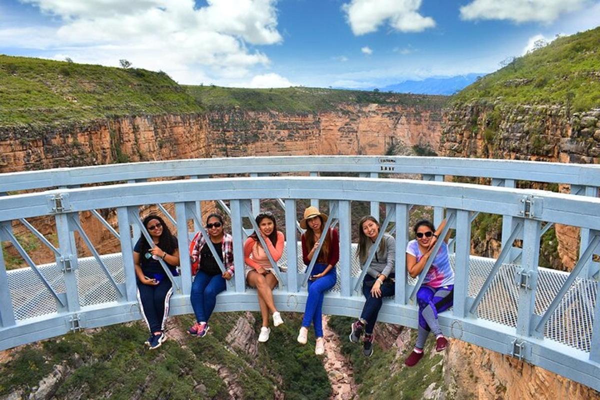 a group of people sitting on a bridge at the grand canyon