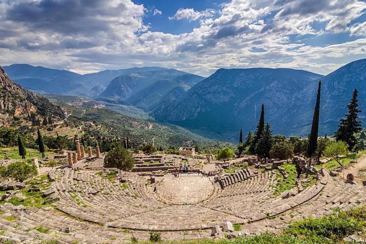 Un anfiteatro en una colina con montañas al fondo.