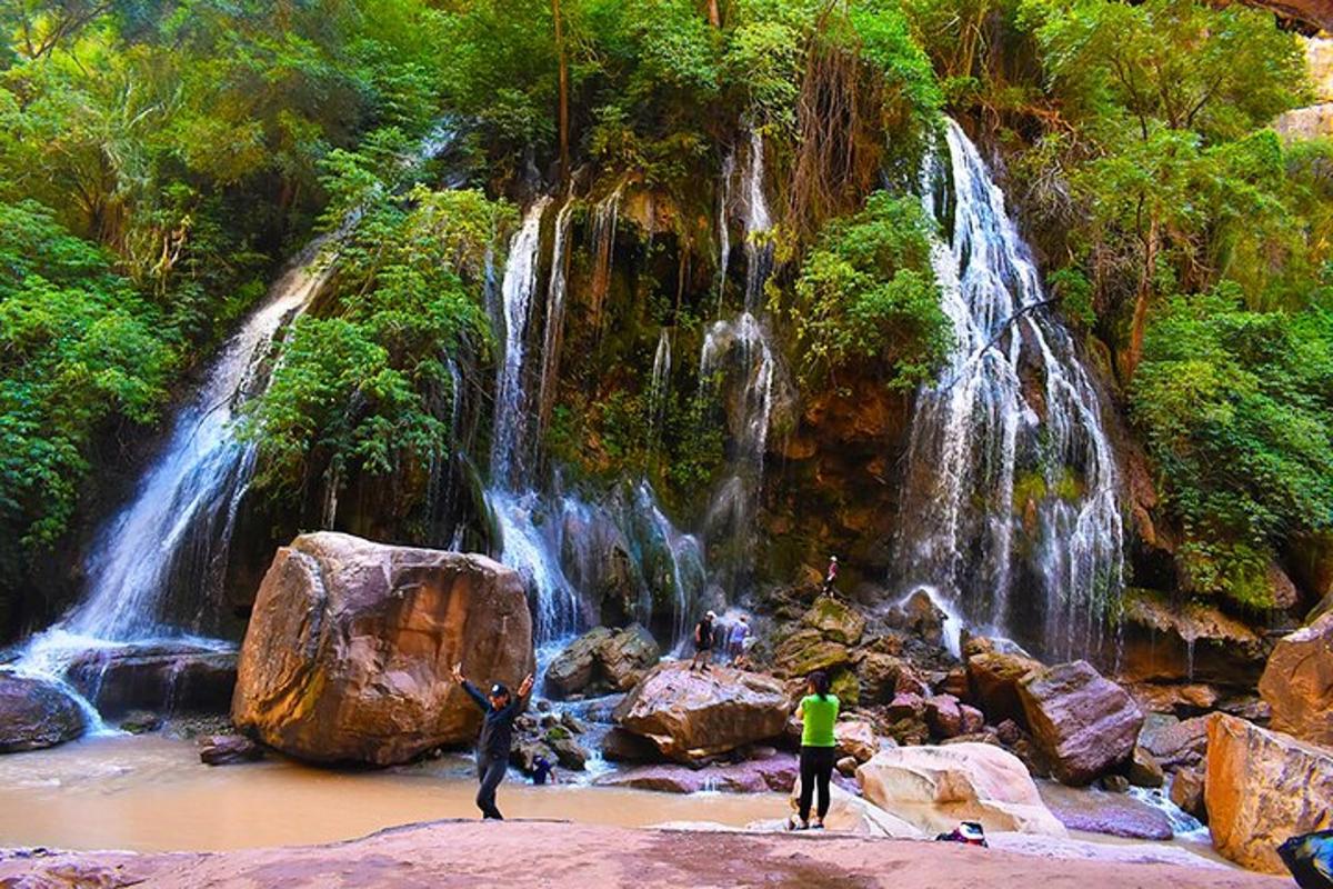 two people standing in front of a waterfall