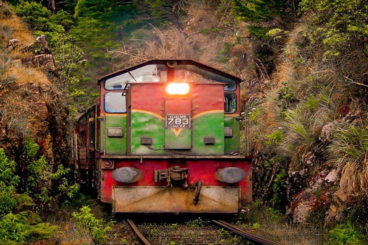 a green and red train traveling down the tracks