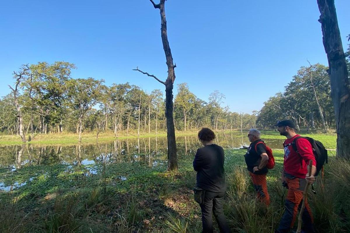 a group of three men standing next to a body of water