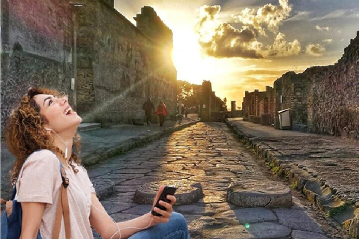 una dona asseguda a terra mirant un telèfon mòbil