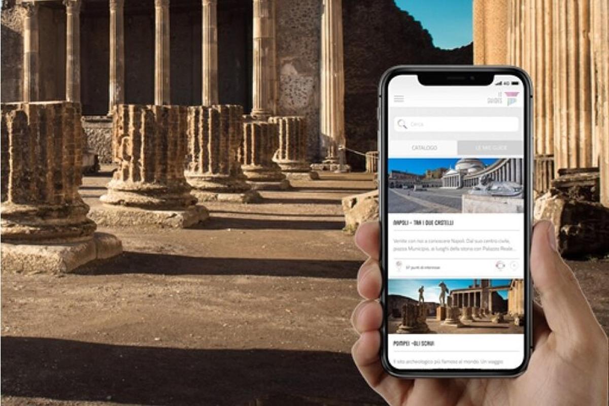 osoba držící mobilní telefon před budovou