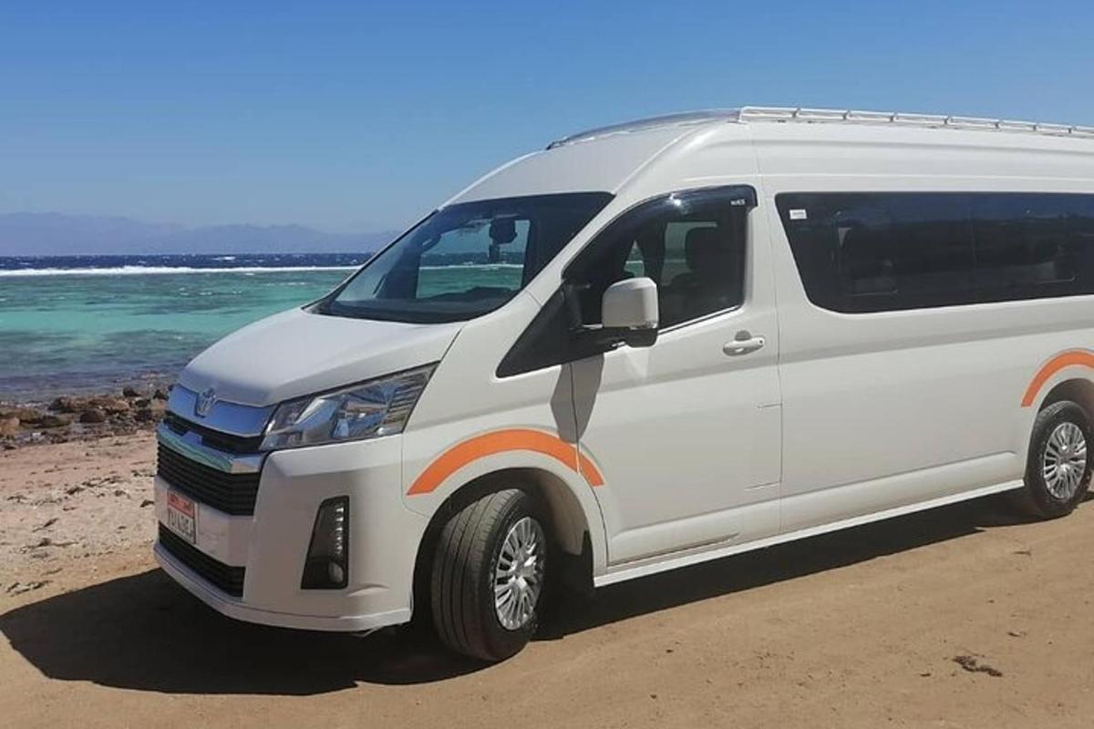 een witte bestelwagen geparkeerd op het strand naast de oceaan