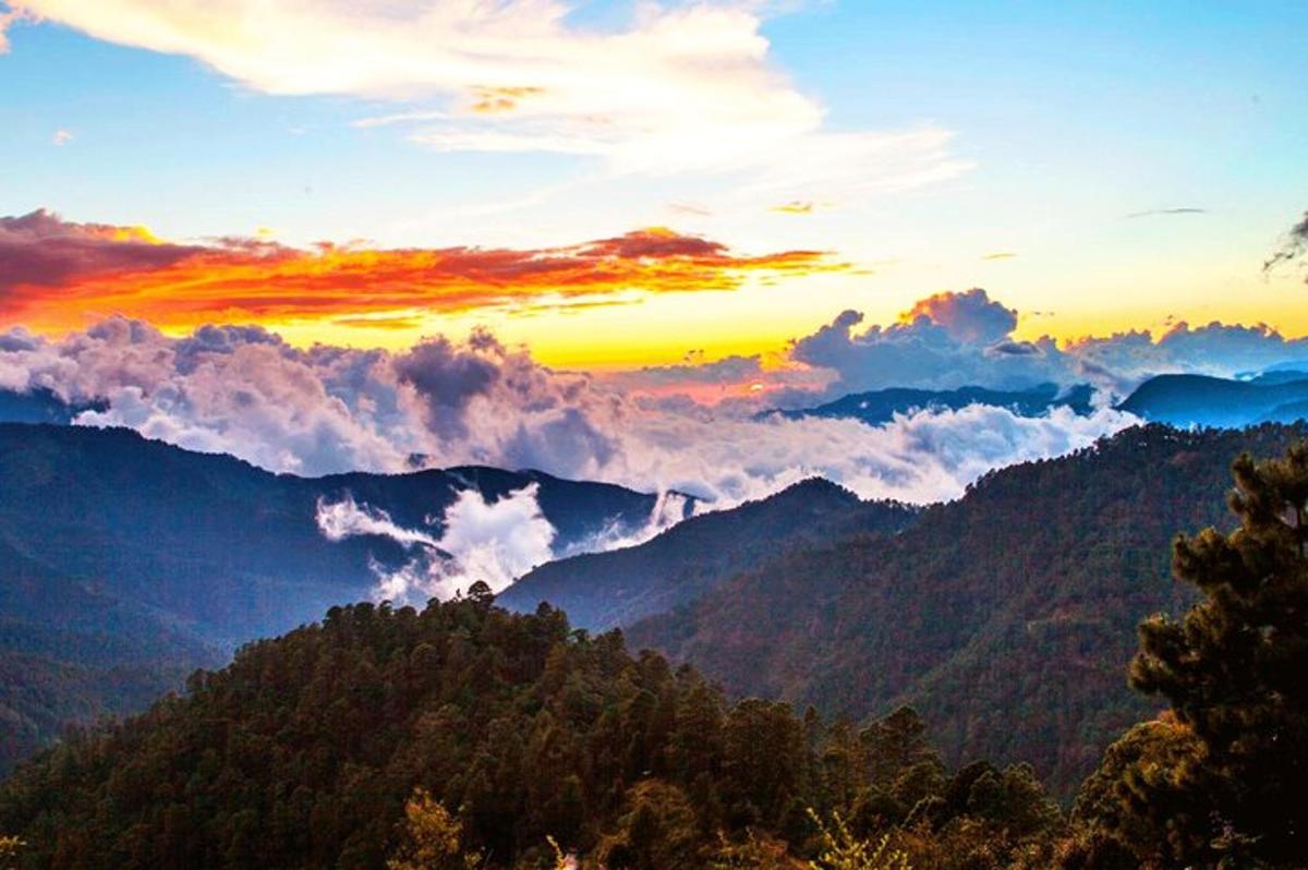 Una puesta de sol sobre una cadena montañosa con nubes en el cielo.