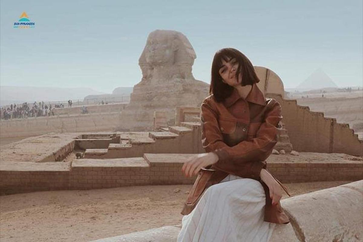 una donna seduta su una sporgenza di fronte a un monumento