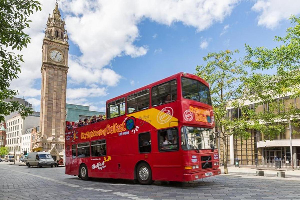a red double decker bus on a street with a clock tower