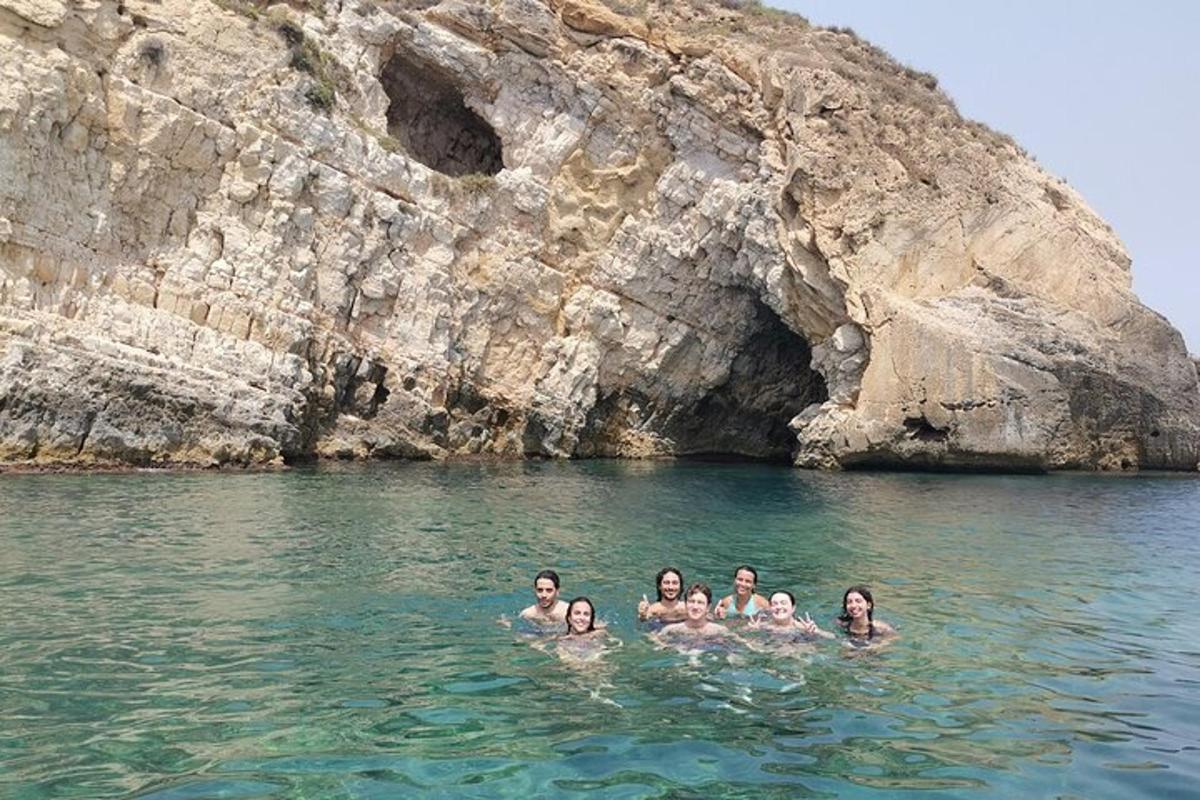 μια ομάδα ανθρώπων στο νερό κοντά σε έναν σχηματισμό βράχου