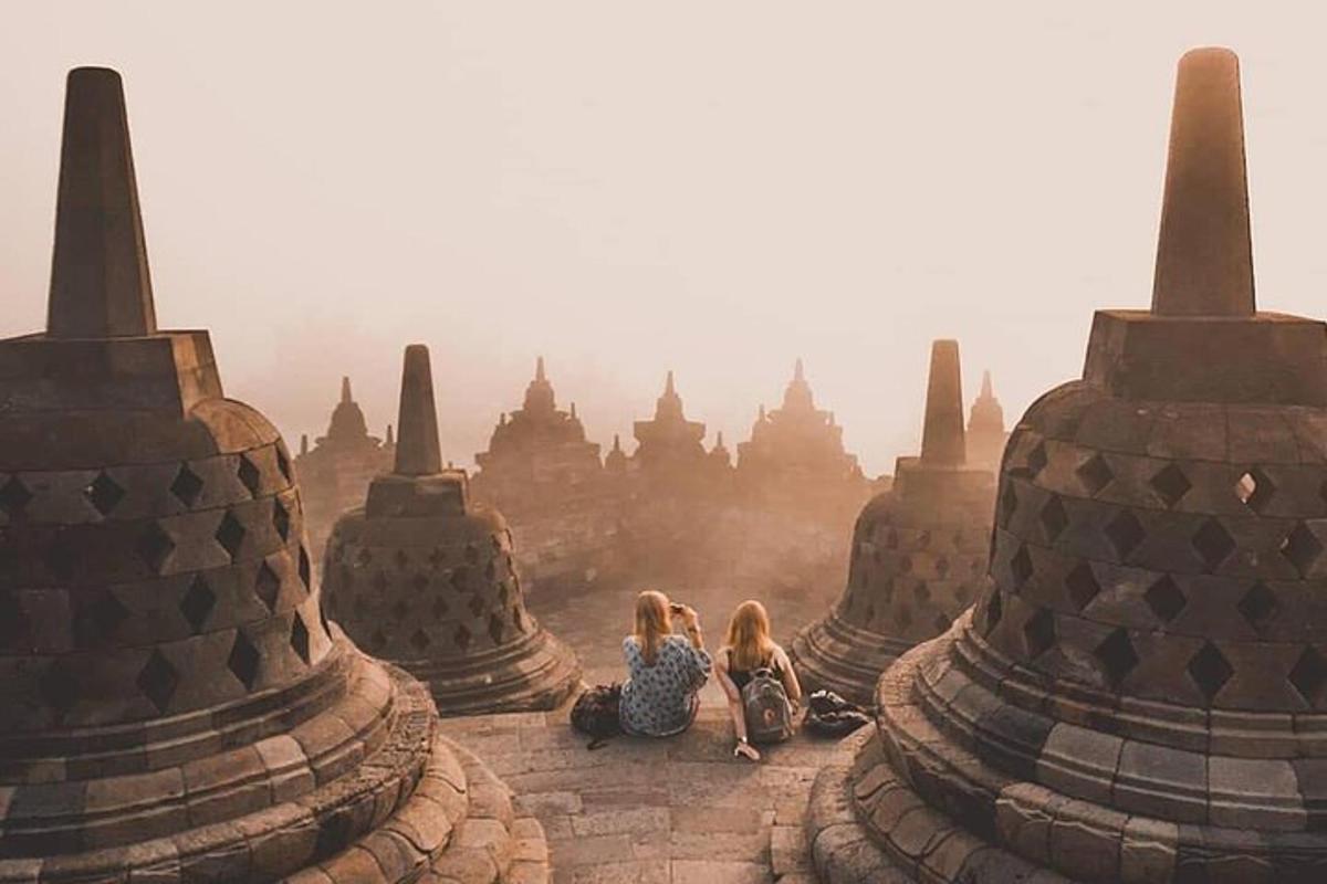 two girls sitting on the steps of an ancient temple