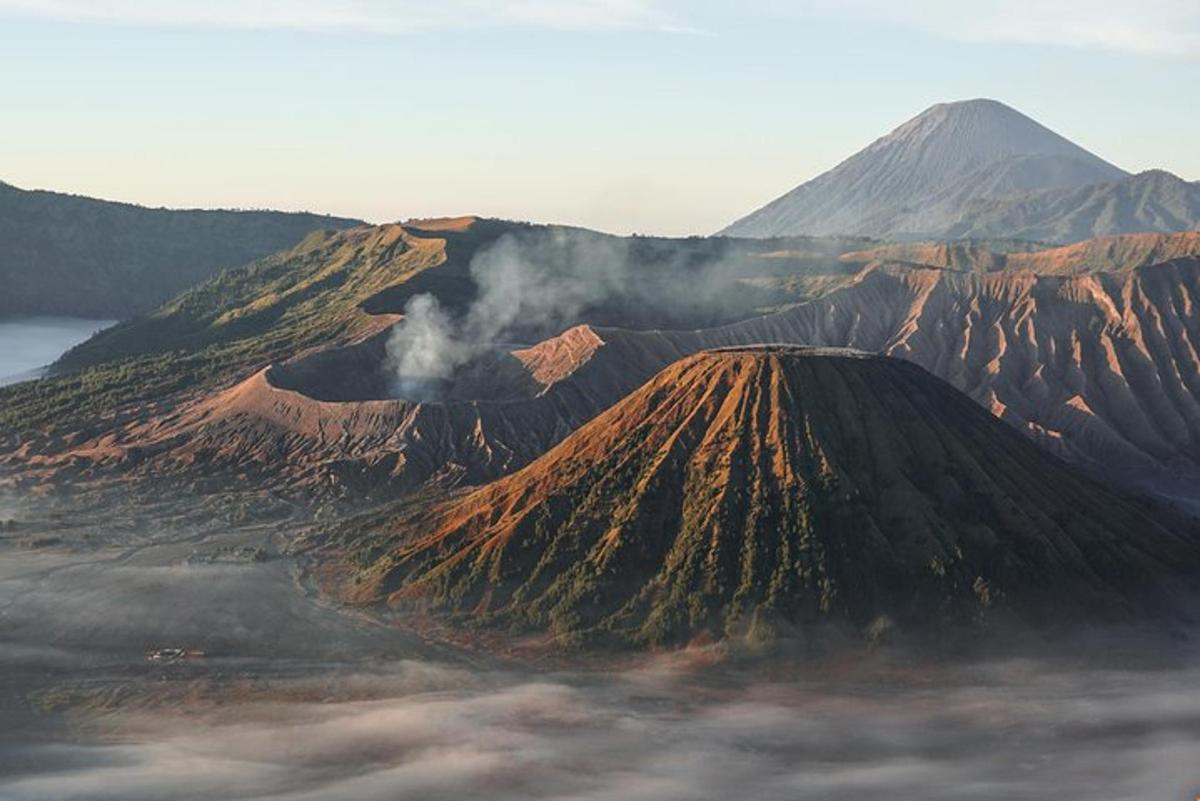 a volcano with smoke coming out of it with a mountain