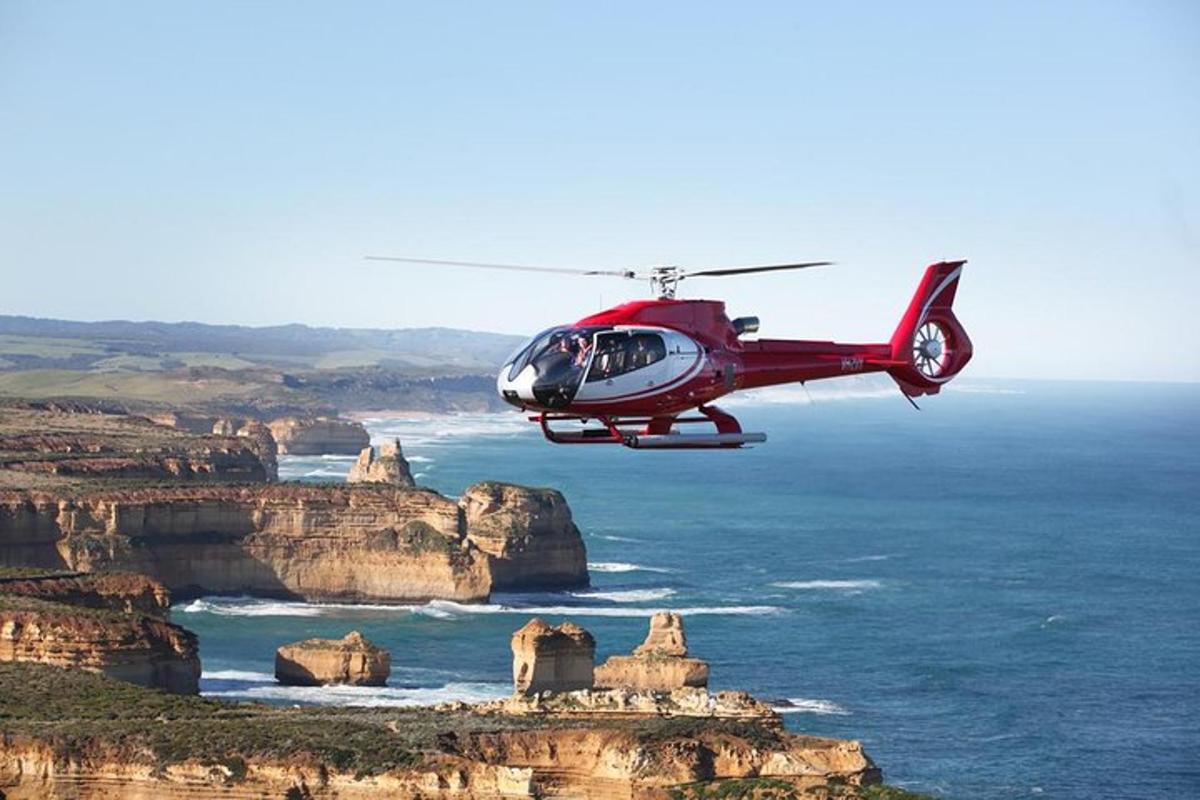 a red helicopter is flying over the ocean