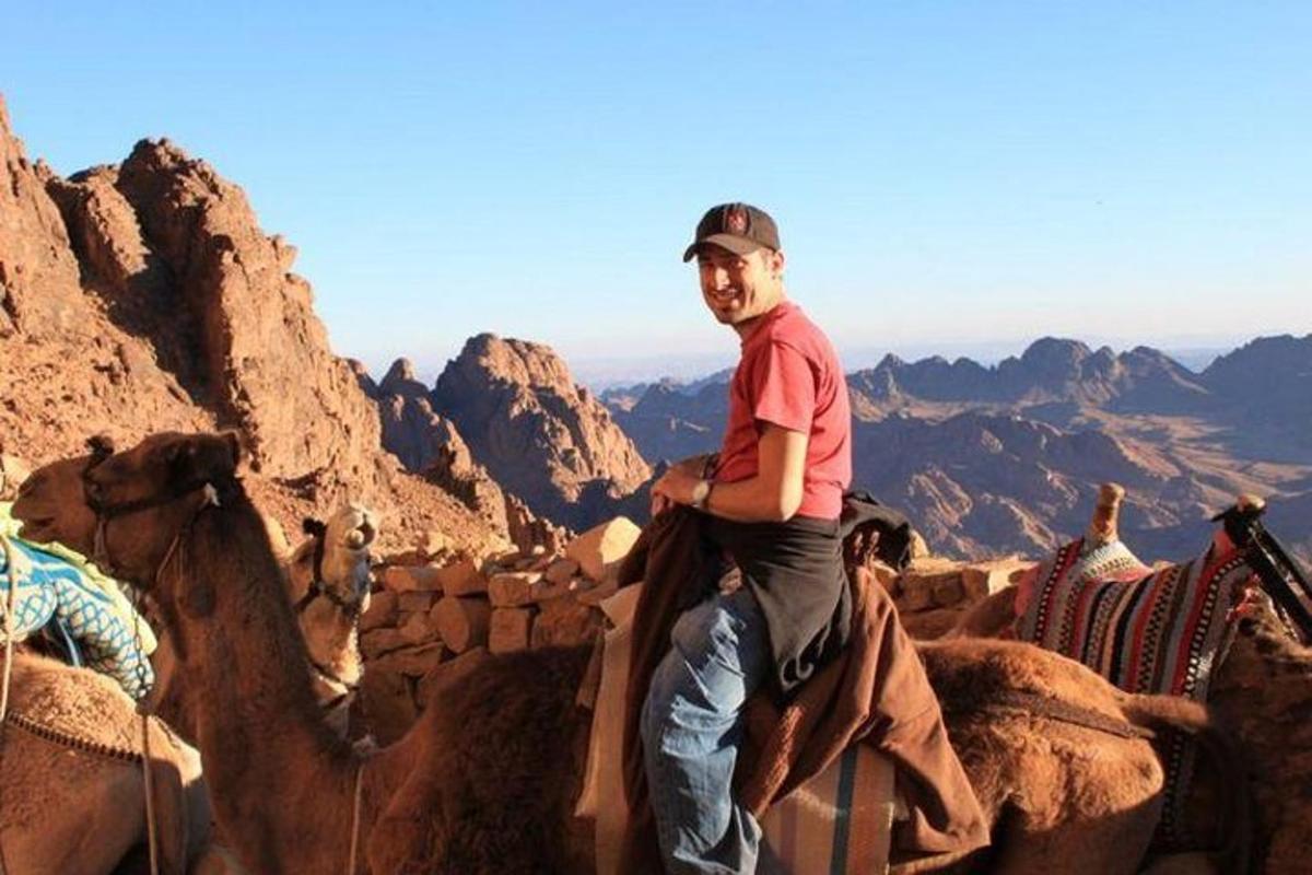 um homem está cavalgando um camelo no deserto