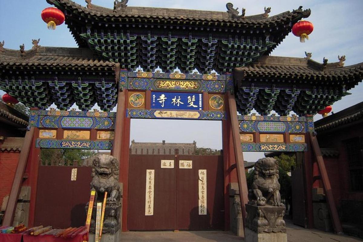 a gate to a temple with two statues in front