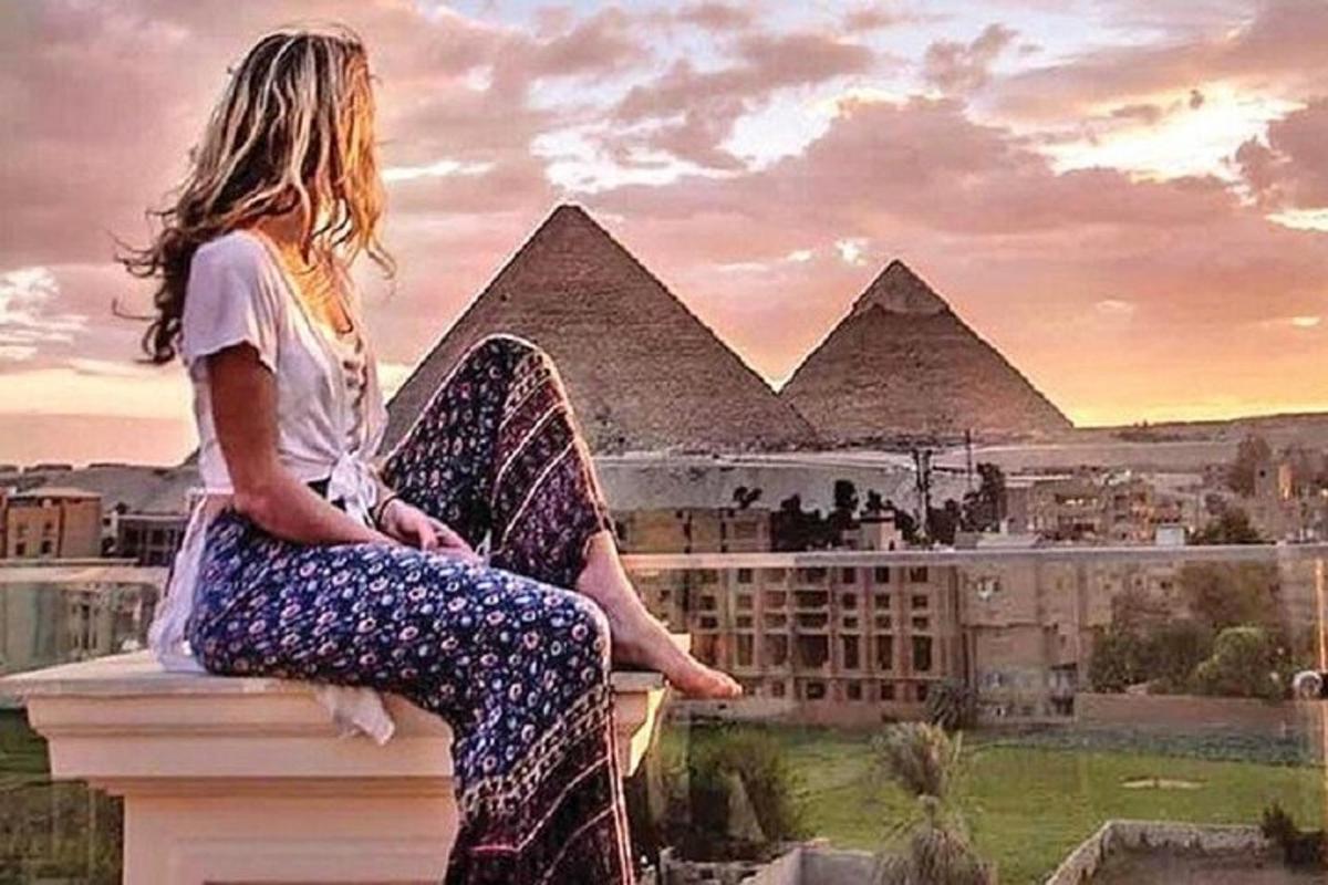 žena sedící na římse a dívající se na pyramidy