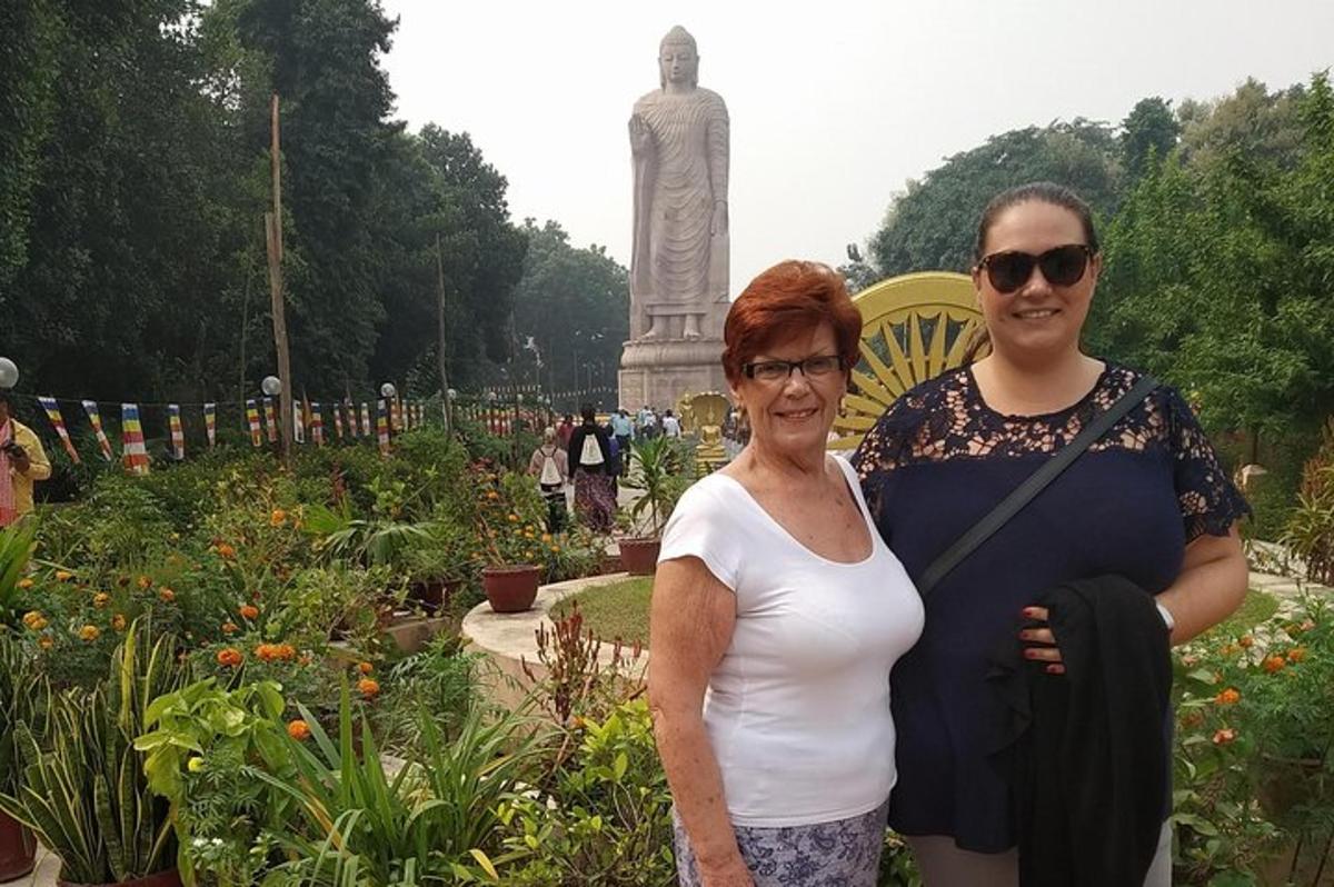 duas mulheres em pé em um jardim com um monumento ao fundo