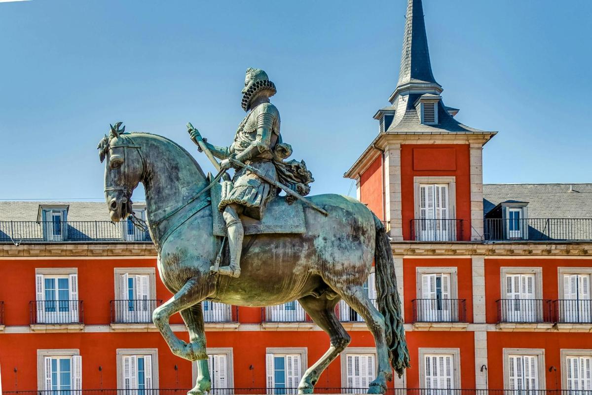 en statue af en mand, der rider på en hest, foran en bygning