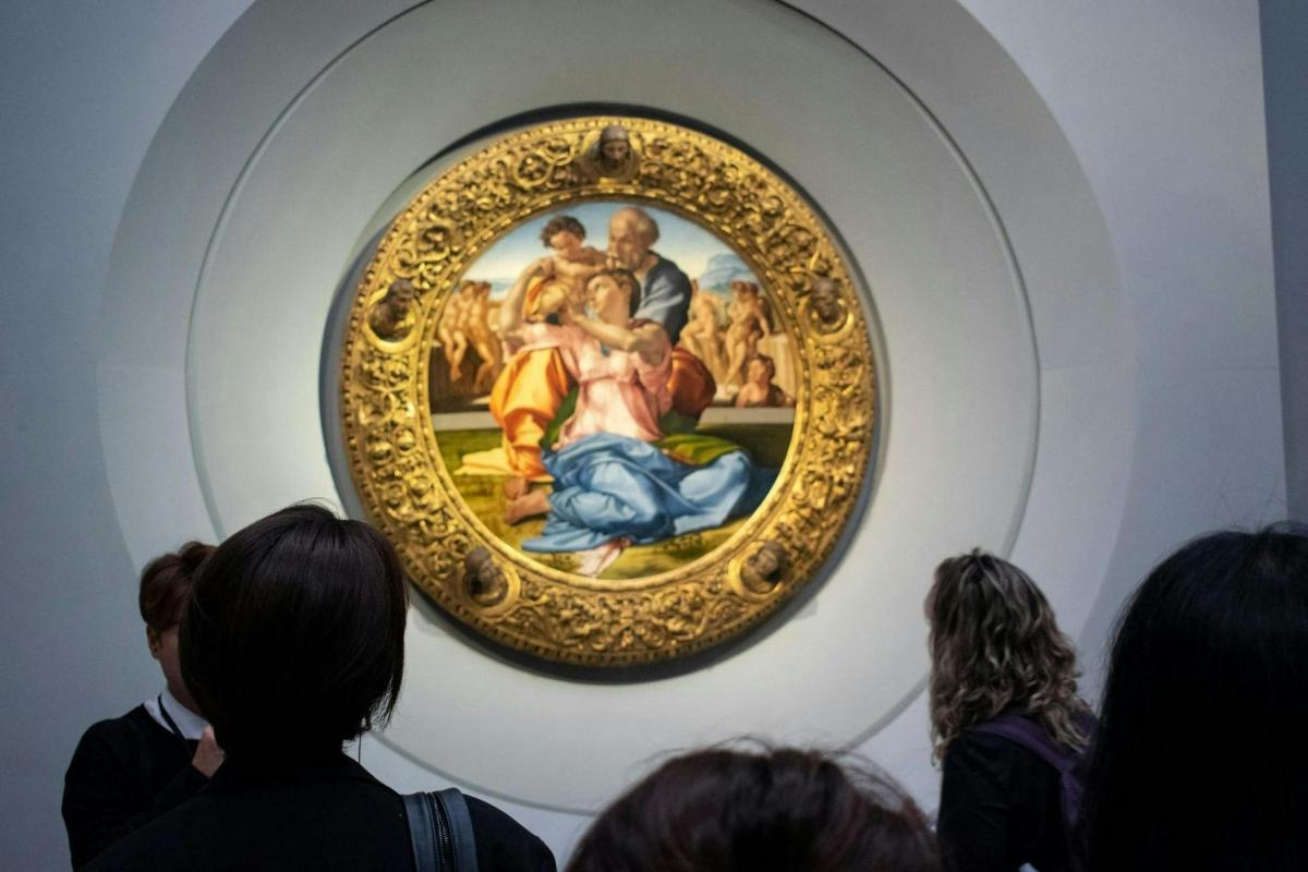 Un grupo de personas mirando una pintura en un museo.