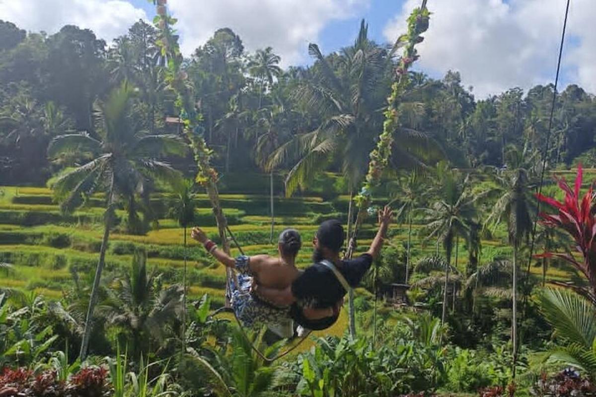 Muž a žena se houpou na zip line nad polem