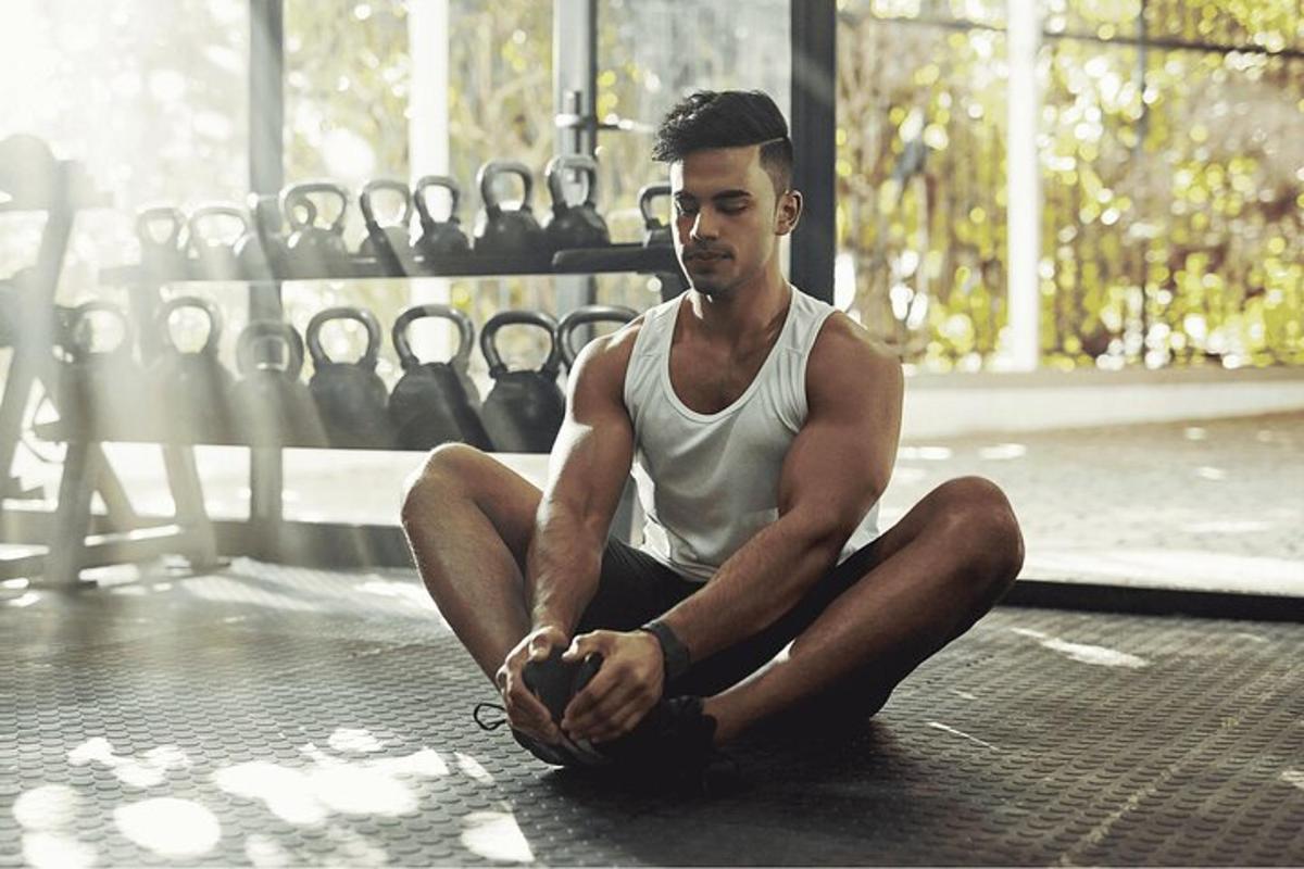 en mand sidder på gulvet i et fitnesscenter
