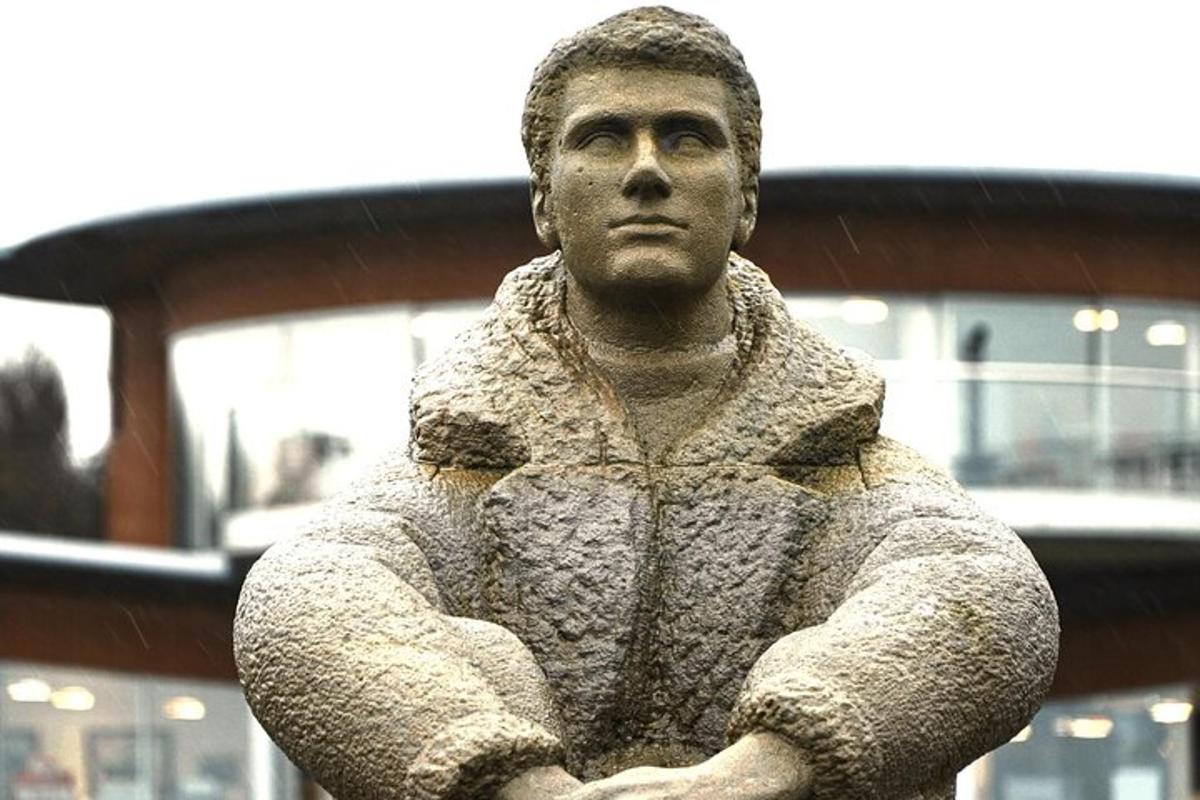 una statua di un uomo in piedi con le braccia incrociate